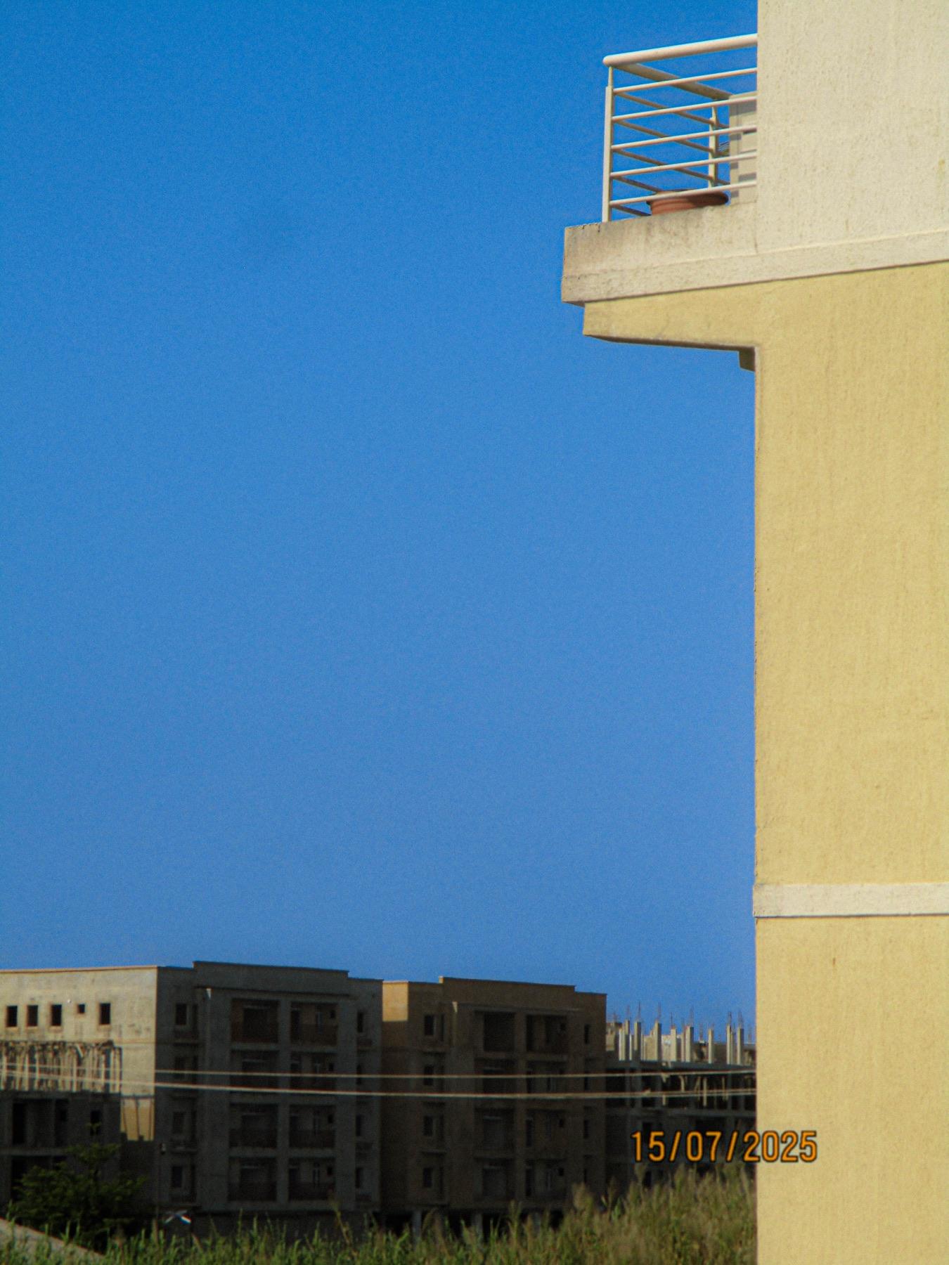 A balcony corner jutting into an empty blue sky