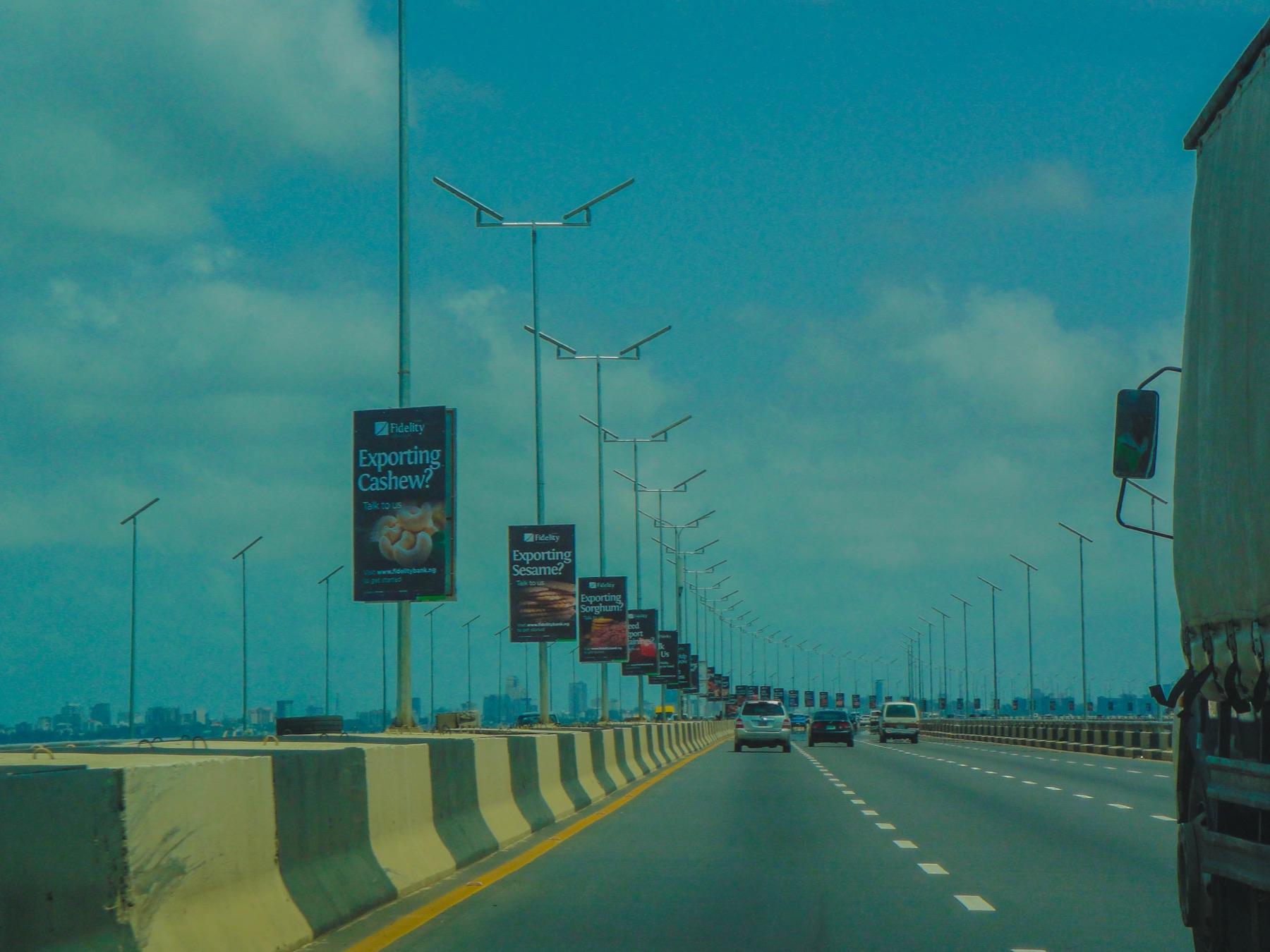Billboards lining a Lagos bridge under a wide blue sky