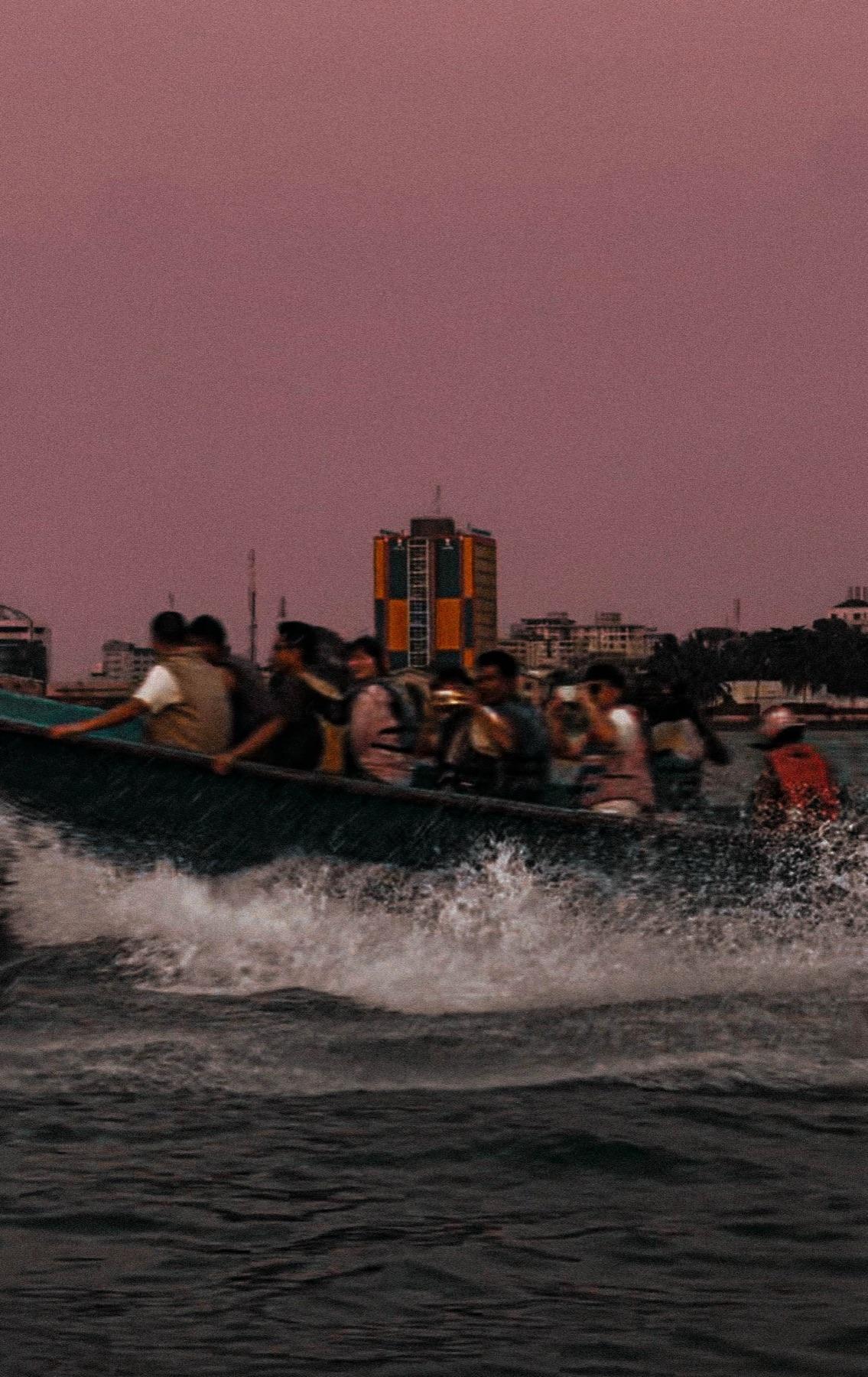 A crowded passenger boat cutting across the Lagos lagoon at dusk