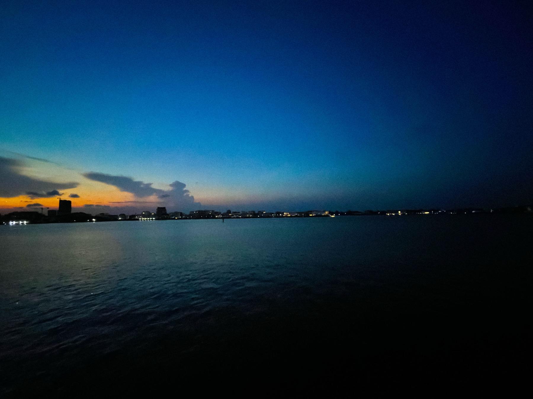 The lagoon at dusk with the city glowing on the horizon